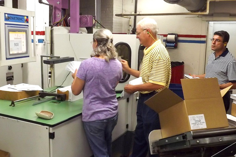 Associates review number 10 envelopes as they come off the envelope folding machine.